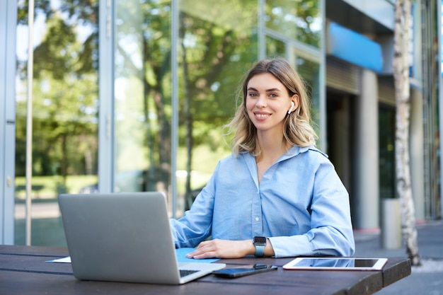 Free photo portrait of young beautiful working woman works on remote with laptop student takes notes during onl