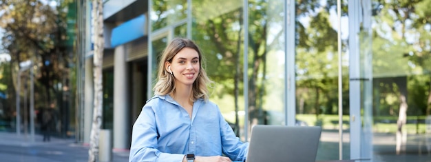 Portrait of young beautiful working woman works on remote with laptop student takes notes during