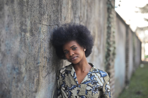 portrait of young black woman leaning against a wall