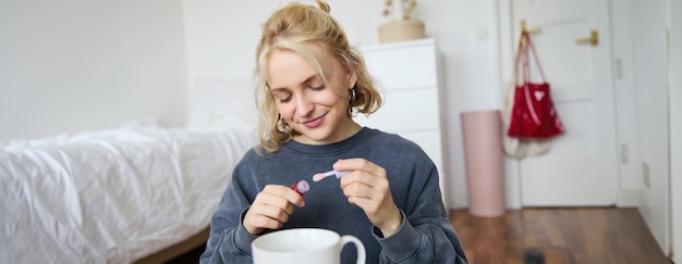 Free photo portrait of young blond girl puts on lip gloss while getting ready for party lifestyle blogger woman