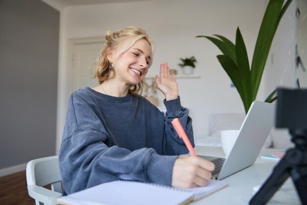 Portrait of young blond smiling woman studying at home remote education concept connects to online