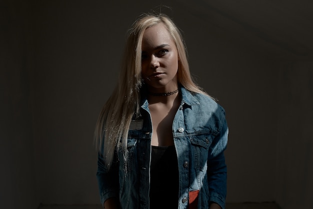 Portrait of young blond woman on dark wall