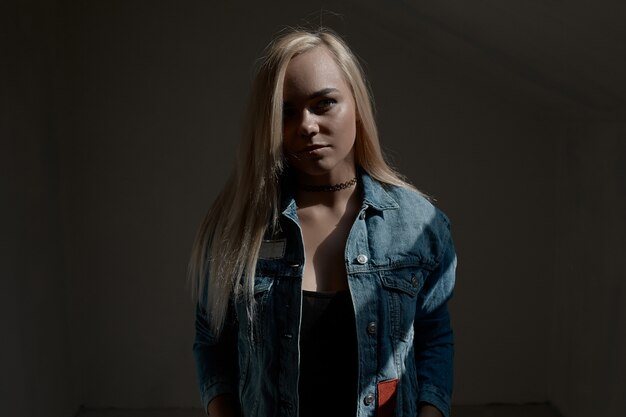 Portrait of young blond woman on dark wall