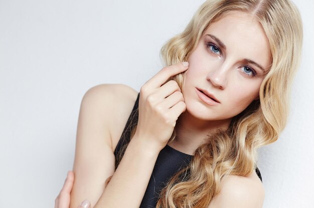 Portrait of young blond woman over grey background.