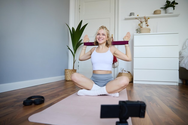 Free photo portrait of young blond woman social media vlogger using digital camera during workout shooting