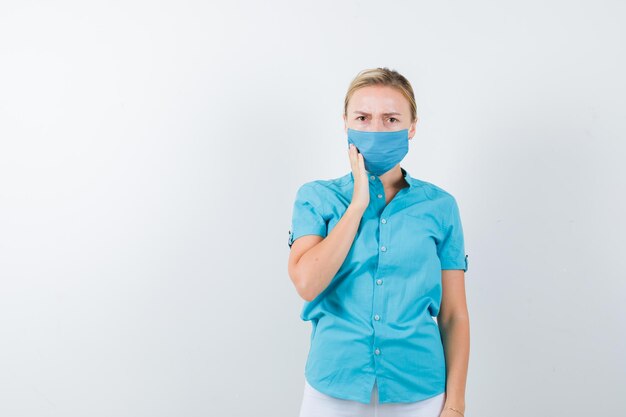 Portrait of young blonde female suffering from toothache in casual clothes