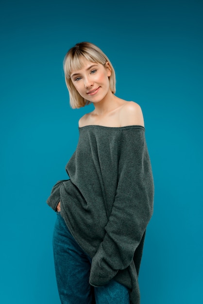 Portrait of young blonde pretty woman over blue wall