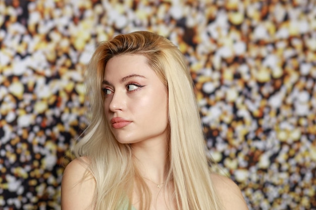 Portrait of young blonde stand on gildede background and looking aside