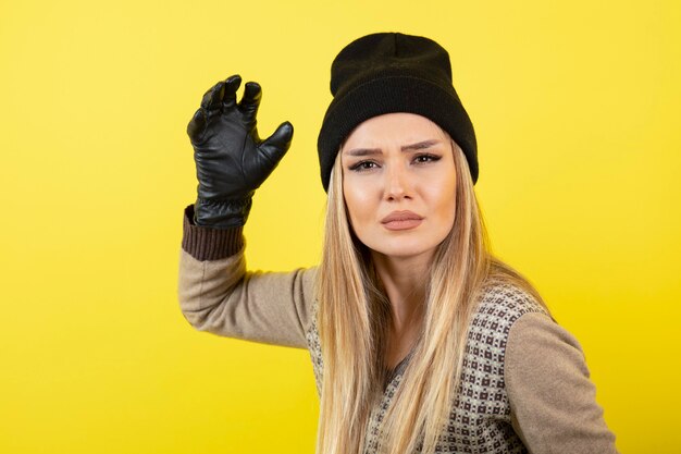 Portrait of young blonde woman in black gloves and hat posing and standing. 