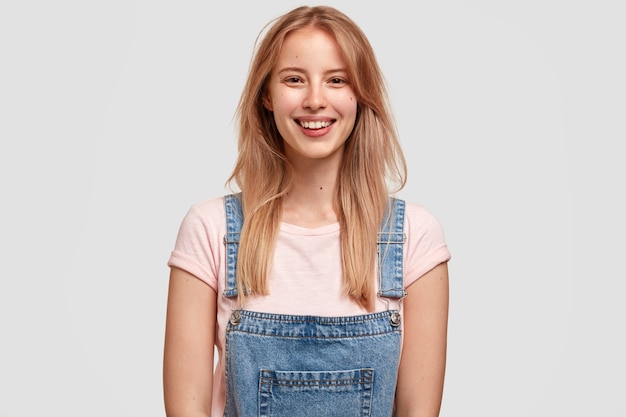 Portrait of young blonde woman in denim overalls