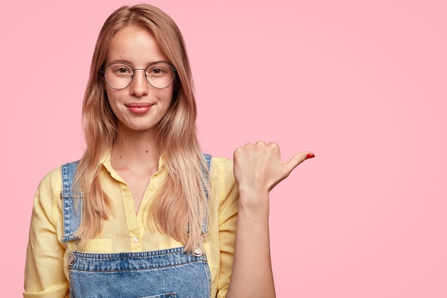 Free photo portrait of young blonde woman in denim overalls