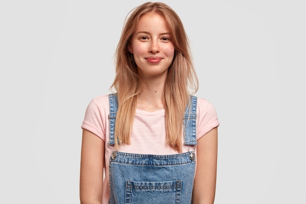 Portrait of young blonde woman in denim overalls