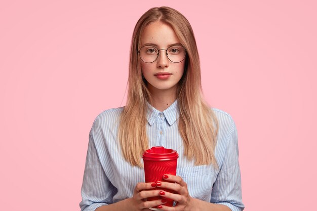 Portrait of young blonde woman holding cup of coffee