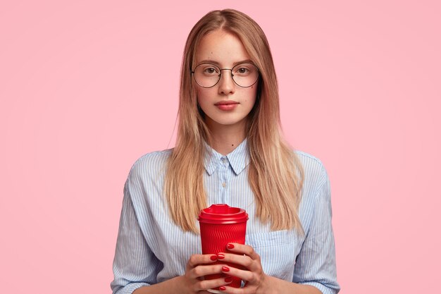 一杯のコーヒーを保持している若いブロンドの女性の肖像画