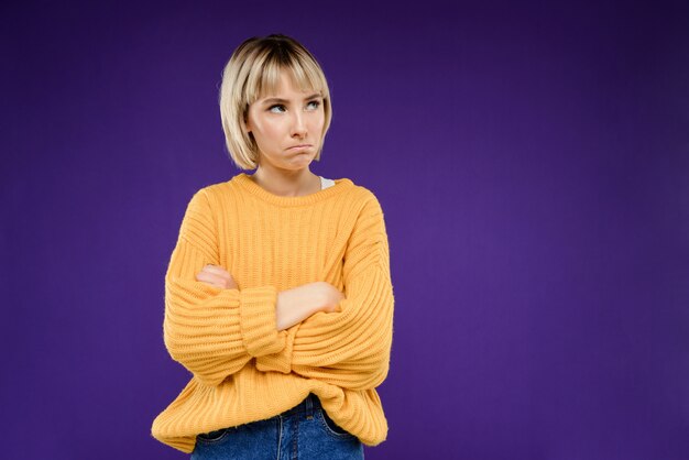 Portrait of young blonde woman over purple wall Copy space