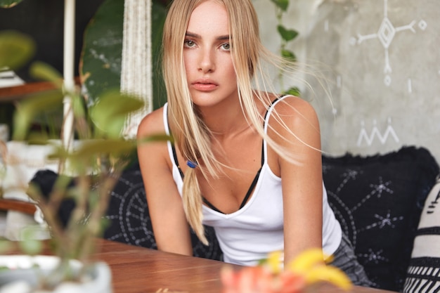 Portrait of young blonde woman sits on a cafe
