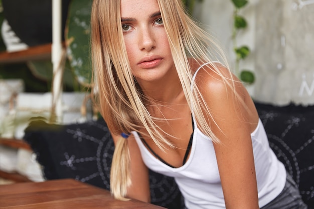 Портрет молодой блондинки сидит в кафе