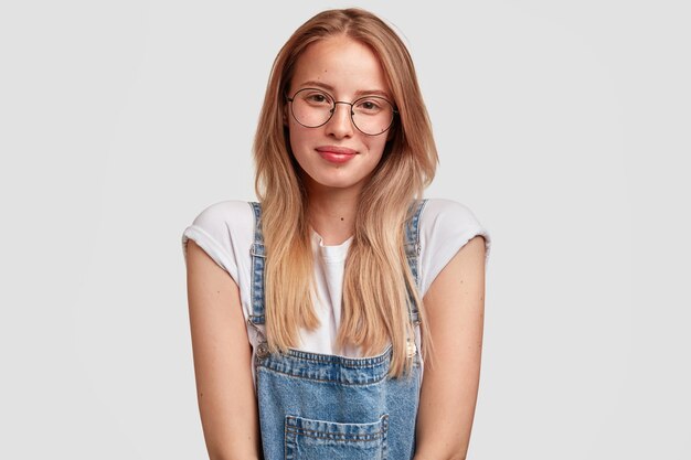 Portrait of young blonde woman wearing denim overalls