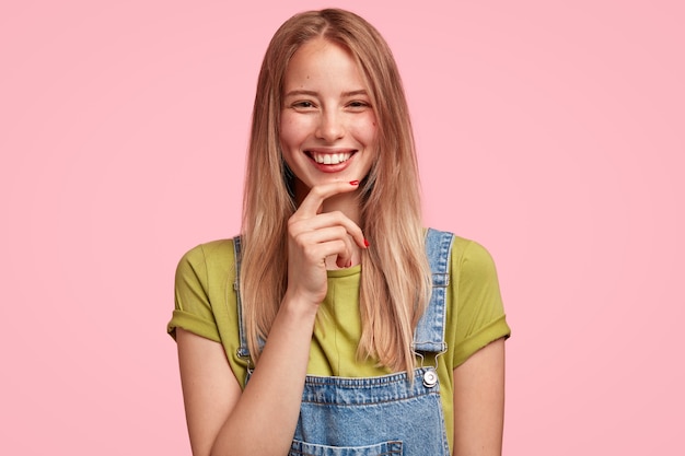 Portrait of young blonde woman wearing denim overalls