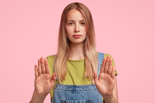 Portrait of young blonde woman wearing denim overalls