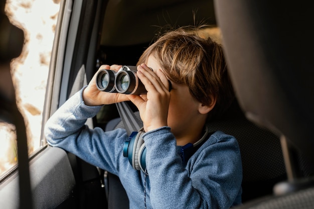 Portrait young boy in car with binoculars