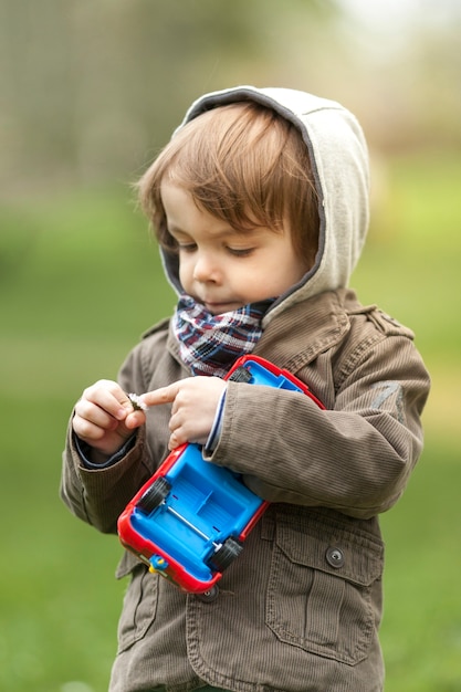 Free photo portrait of young boy checking a flower