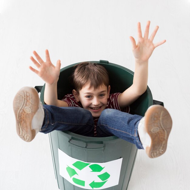 Portrait of young boy posing inside of recycle bin