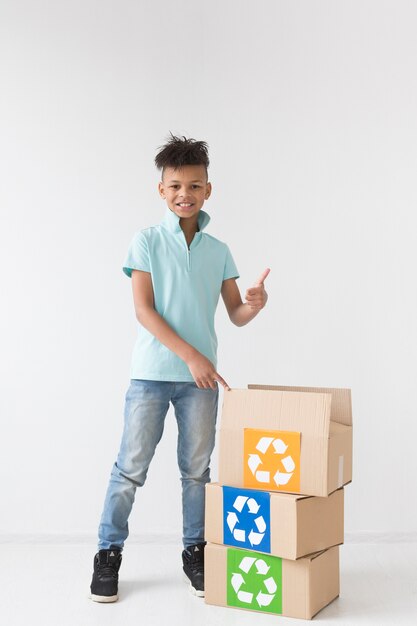 Portrait of young boy posing with recycling boxes