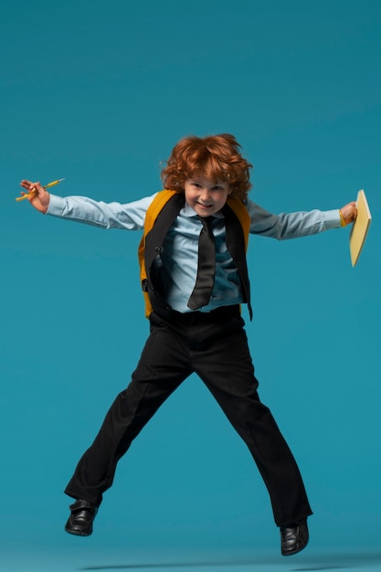 Portrait of young boy student in school uniform jumping mid-air