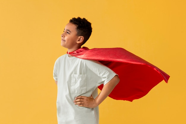 Free photo portrait of young boy with superhero cape