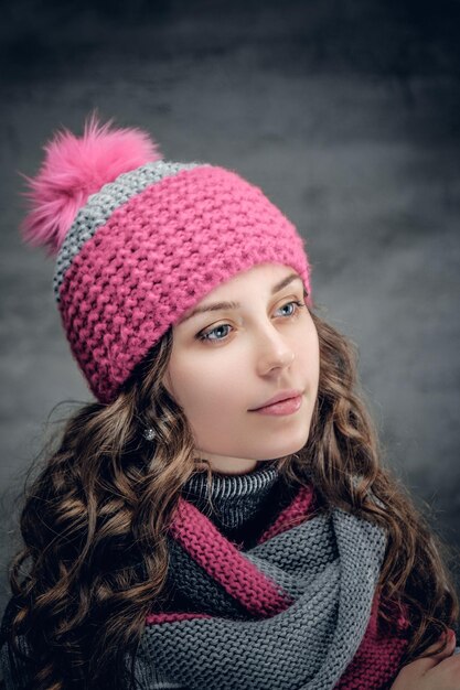 Portrait of young brunette female with curly hair in winter hat and a scarf.