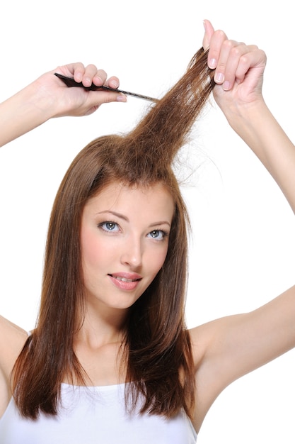 Free photo portrait of young brunette girl doing backcombing with comb