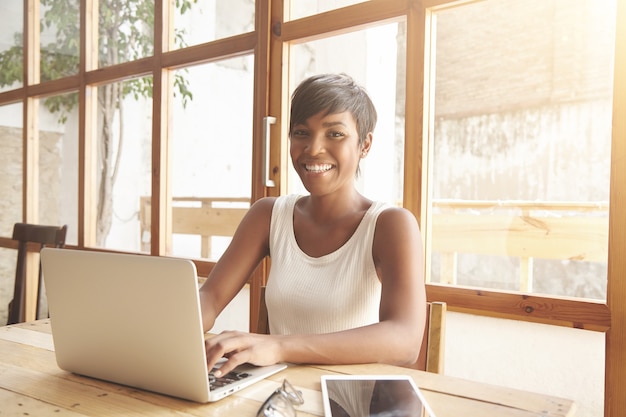 Portrait of young brunette woman sitting in cafe with laptop