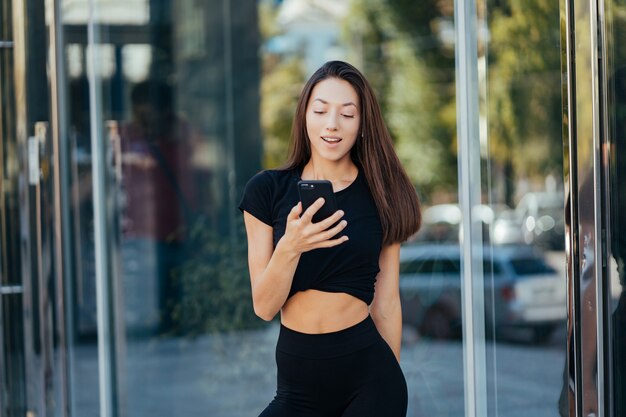 Portrait of a young brunette woman with headphones and smiling while walking