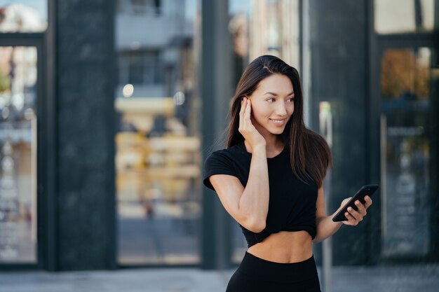 Portrait of a young brunette woman with headphones and smiling while walking