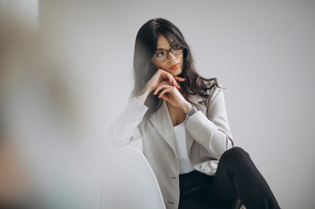 Портрет молодой женщины, сидя в офисе