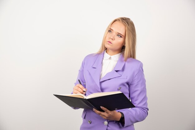 Portrait of young business woman standing and holding clipboard. 