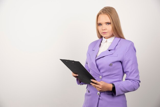 Portrait of young business woman standing and holding clipboard.