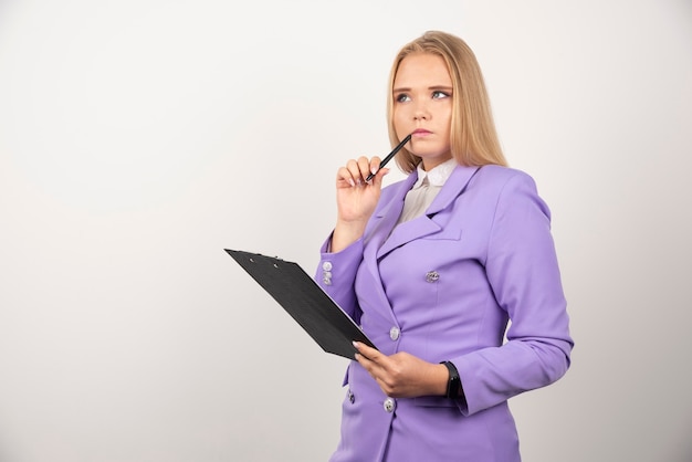 Portrait of young business woman standing and holding clipboard.