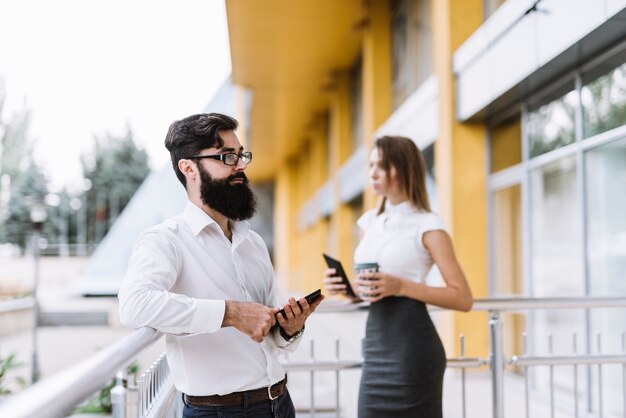 Free photo portrait of young businessman and businesswoman standing in the balcony