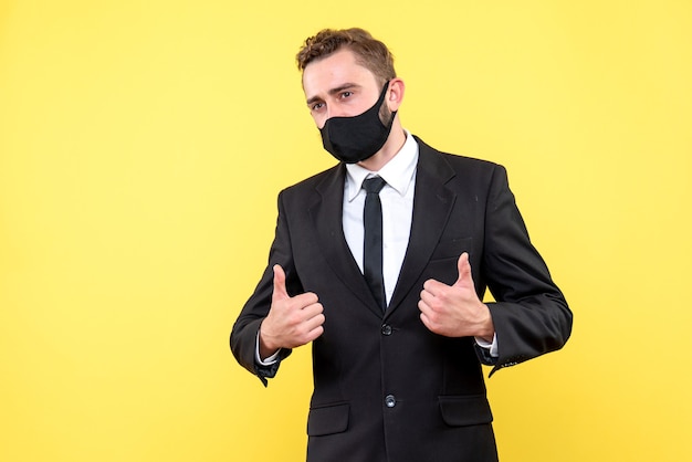 Portrait of young businessman with thumbs up sign on yellow