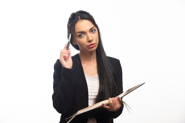 Portrait of young businesswoman holding notebook with pen