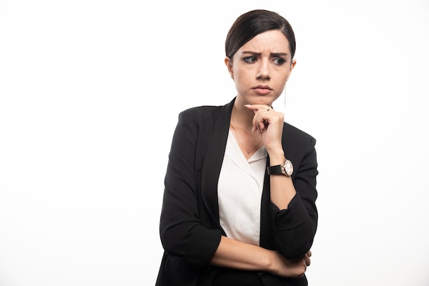 Portrait of young businesswoman posing on white wall.