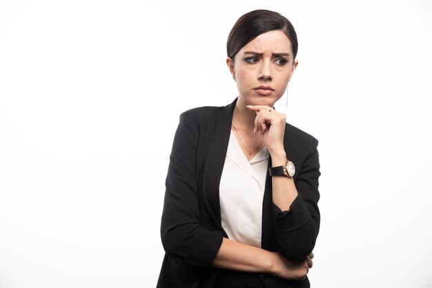 Portrait of young businesswoman posing on white wall.