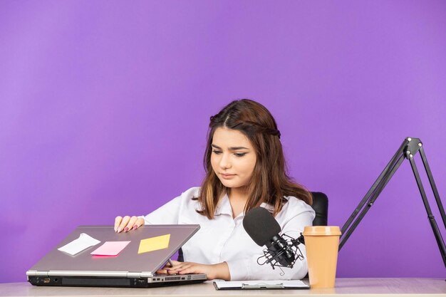 Portrait of a young businesswoman sitting behind the desk and opening her notebook High quality photo