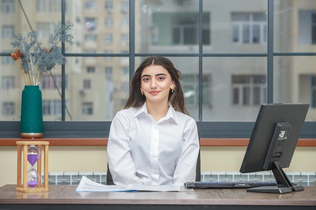 Portrait of a young businesswoman sitting at the desk and smiling to the camera