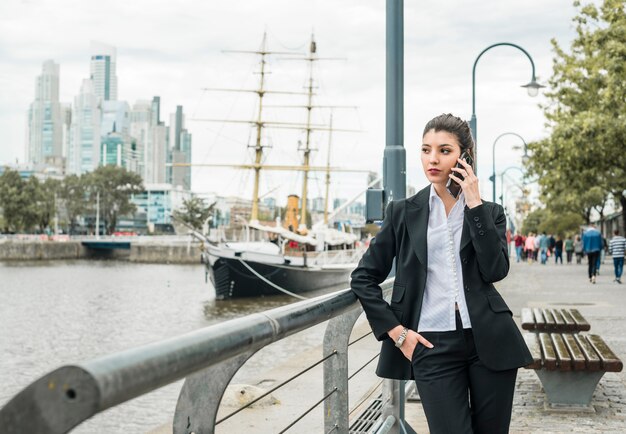 Portrait of a young businesswoman talking on cell phone leaning near the railing