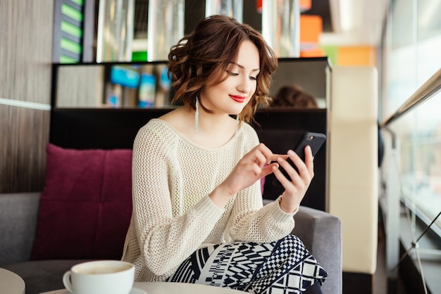 Portrait of young businesswoman use mobile phone while sitting in comfortable coffee shop