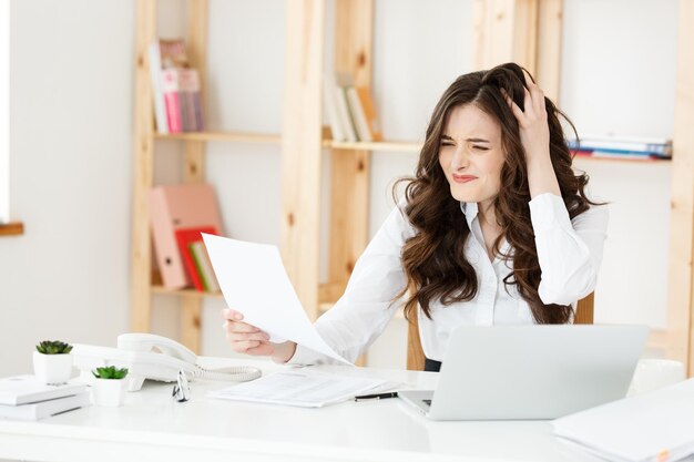 Portrait of Young Businesswoman working in her office with serious facial expression with document report