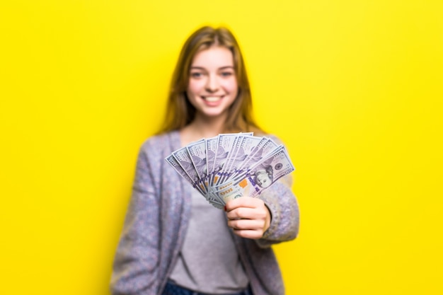 Portrait of a young casual teen girl holding money banknotes isolated